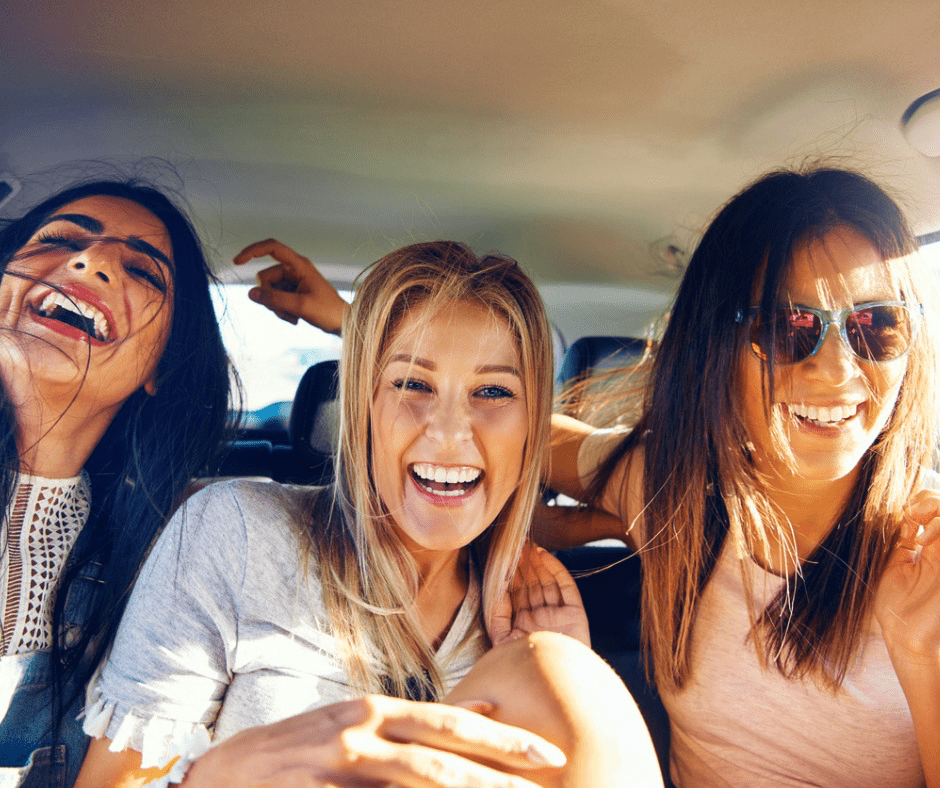 Three women riding in a car happy and laughing in summertime- Vedas Medical Spa & Wellness Center